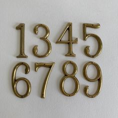 brass numbers and numerals are displayed on a white surface, including one for each number