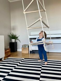 a young child is playing on a swing set in the living room with his feet up