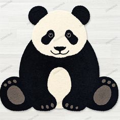 a black and white panda bear rug sitting on top of a wooden floor