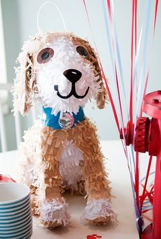 a dog made out of toilet paper sitting next to a fire hydrant and balloons