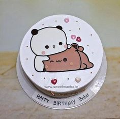 a white cake with a bear on it sitting on top of a counter next to a cupcake