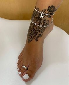 a woman's foot with a tattoo on it and a chain around the ankle