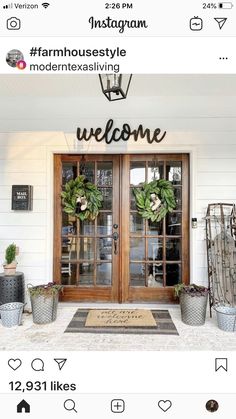 a welcome sign on the front door of a white house with potted plants and wreaths