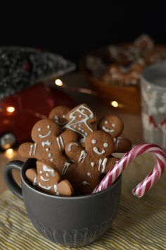 a cup filled with cookies and candy canes on top of a table next to candles