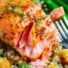 a piece of salmon on top of rice with a fork next to some asparagus