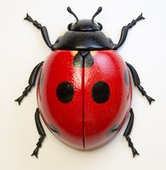 a red lady bug sitting on top of a white wall