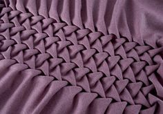 a close up view of a bed with purple sheets and blankets on top of it