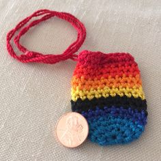 a small crocheted bag with a coin on the side and a red string attached to it