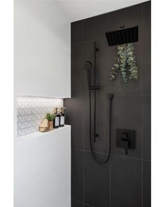 a bathroom with a shower head, hand held shower faucet and tiled walls