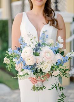 a bride holding a bouquet of flowers in her hands and smiling at the camera while standing outside