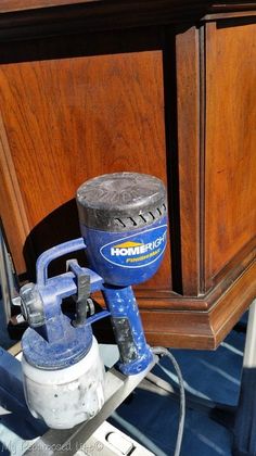 a blue and white paint sprayer sitting on top of a wooden cabinet next to a tool