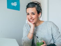 a woman sitting at a table with a green smoothie