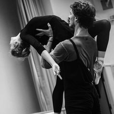 two ballerinas in black and white pose for the camera while one holds on to his leg