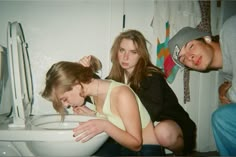 three young people standing around a toilet in a bathroom