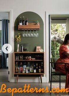 a woman sitting at a table in front of a wine rack with bottles and glasses on it