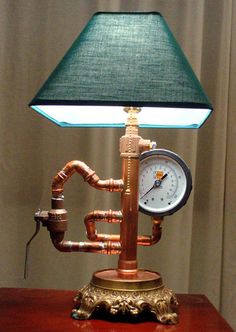 a lamp that is sitting on top of a table with pipes and a clock underneath it