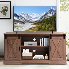 a flat screen tv sitting on top of a wooden entertainment center next to a window