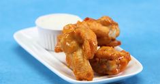 some fried food on a white plate with ranch dressing in the middle and dipping sauce