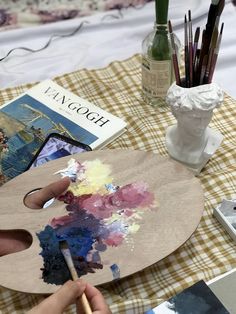 a person is painting on an easel with watercolors and paintbrushes