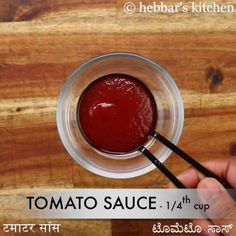 tomato sauce in a small glass bowl with a black spoon on a wooden table top