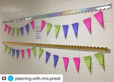 a bulletin board with pink, green and blue pennants hanging from it's sides