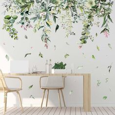 a dining room table with two chairs and a wall mural behind it that has green leaves on it