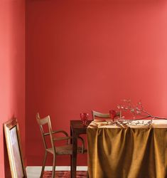 a dining room with red walls and a table in the middle, surrounded by two chairs