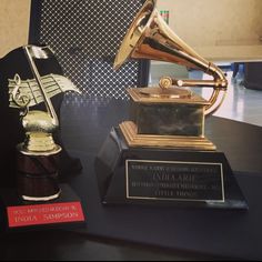 two trophies sitting on top of a table next to each other, one gold and the other black