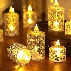 several lit candles sitting on top of a wooden table next to each other with lights in them