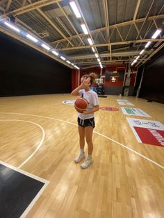 a woman standing on top of a basketball court holding a ball in her right hand