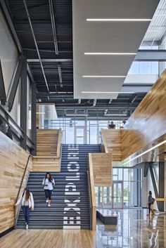 two people are walking up the stairs in an office building with wood and metal railings