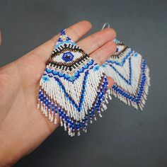 a hand is holding some beaded items in it's palm and the beads are blue and white