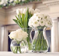 three vases filled with white flowers on top of a table