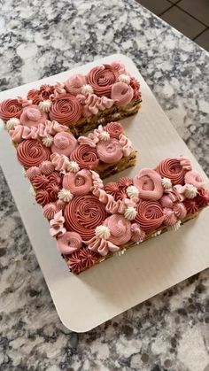 the letter e is made out of pink frosting and rolled up flowers on top of it