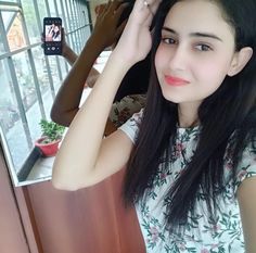 a woman with long black hair is taking a selfie in front of a window