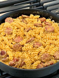 a skillet filled with pasta and meatballs on top of an oven burner