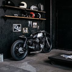 a motorcycle parked in front of a black wall with pictures on it and shelves above