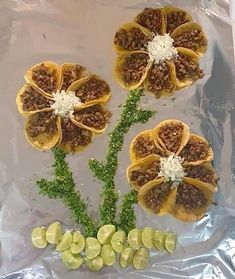 some food is laying on top of tin foil and has flowers made out of it