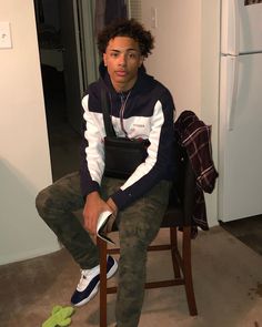 a young man sitting on top of a wooden chair