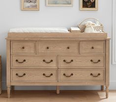 a baby's bed and dresser in a room with pictures on the wall above it