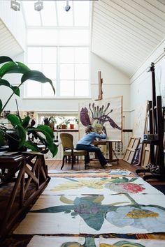 a man sitting on a chair in front of a large rug with flowers and plants