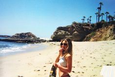 a woman is on the beach talking on her cell phone and holding a wine bottle