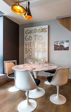 a dining room table with four chairs and an art piece on the wall behind it