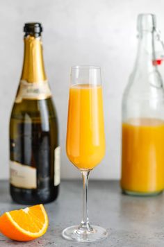 an orange juice in a glass next to two bottles