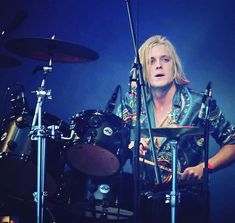 a man with blonde hair playing drums on stage