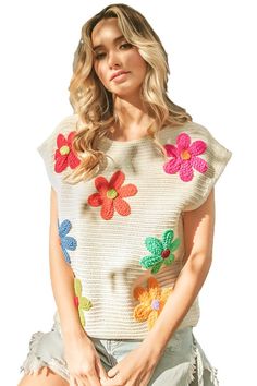 a woman in shorts and a sweater with crochet flowers on the front is posing