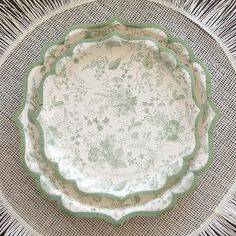 a green and white plate sitting on top of a woven tablecloth covered placemat