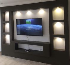 a flat screen tv mounted to the side of a wall in a living room with recessed lighting