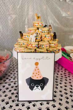 a table topped with cookies and cupcakes next to a bowl of dog treats