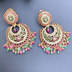 Traditional chandbali / brijbala earrings in sterling silver with 22K gold plating. Set with freshwater pearls and synthetic rubies and emeralds. The hanging beads are real rubies and emeralds. All our Gold Plated Jewellery is made using 925 Silver as the base metal. The beads in hanging and strings (like in our 22k gold jewelry) are always precious freshwater pearls and high quality ruby, emerald and sapphire beads. The default choice for studded stones is precious freshwater pearls and the red Festival Jeweled Chandbali Pearl Earrings, Festival Chandbali Pearl Earrings With Jewels, Fusion Chandbali Bridal Earrings With Jewels, Green 22k Gold Chandbali Earrings, Fusion Style Chandbali Bridal Earrings With Jewels, Fusion Style Jeweled Chandbali Bridal Earrings, 22k Gold Green Chandbali Earrings, 22k Gold Chandbali Chandelier Earrings, Fusion Style Jeweled Chandbali Earrings